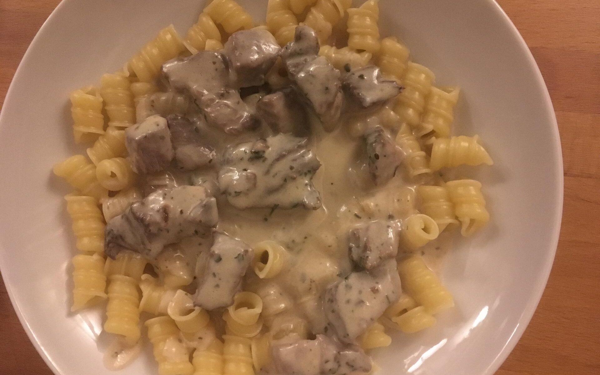 Ein Tellergericht mit Nudeln und Steakwürfeln in Parmesansauce