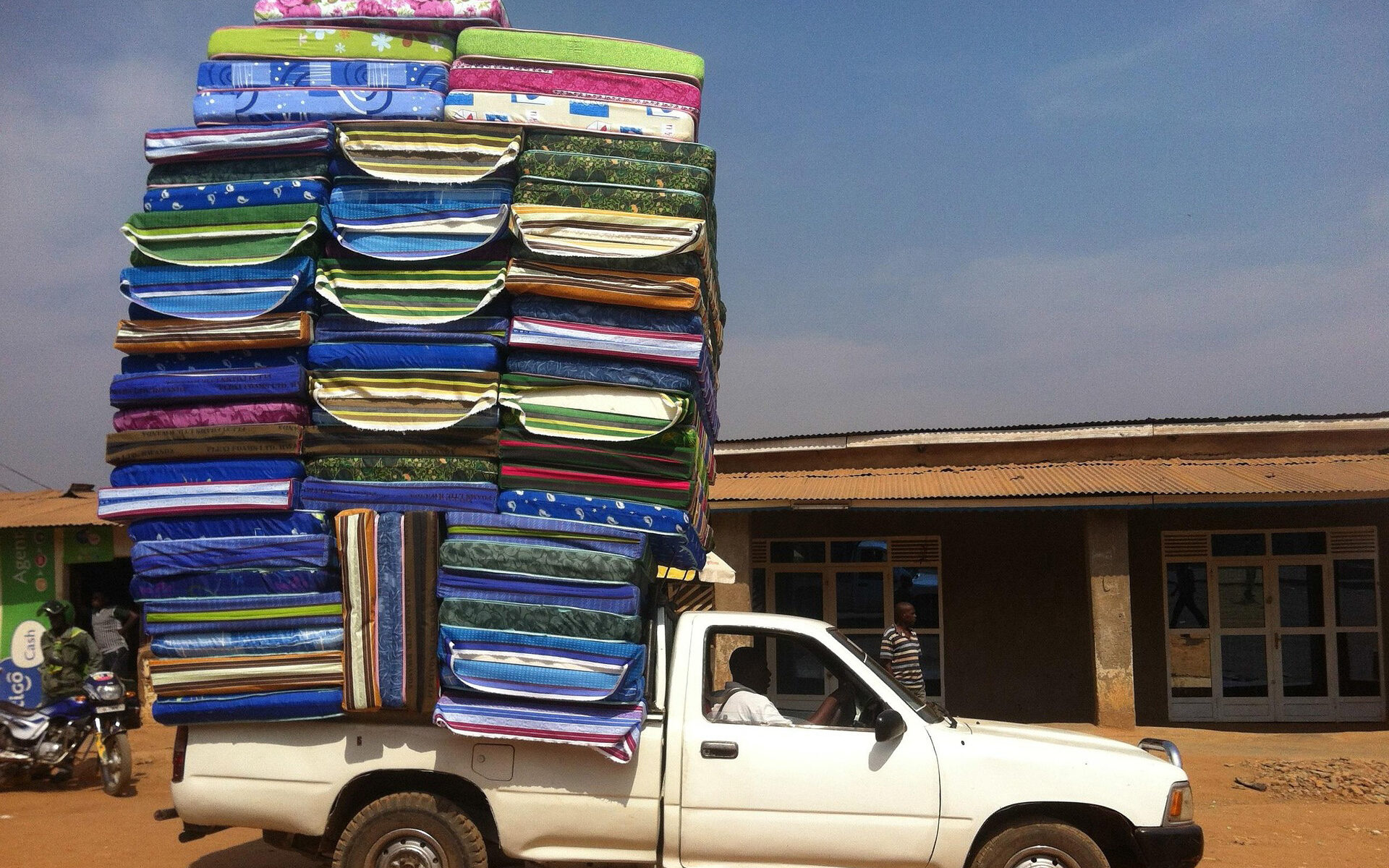 Bild eines überladenen Pickups. Ladung: Bunte Matrazen.