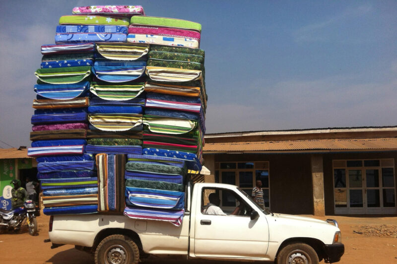 Bild eines überladenen Pickups. Ladung: Bunte Matrazen.