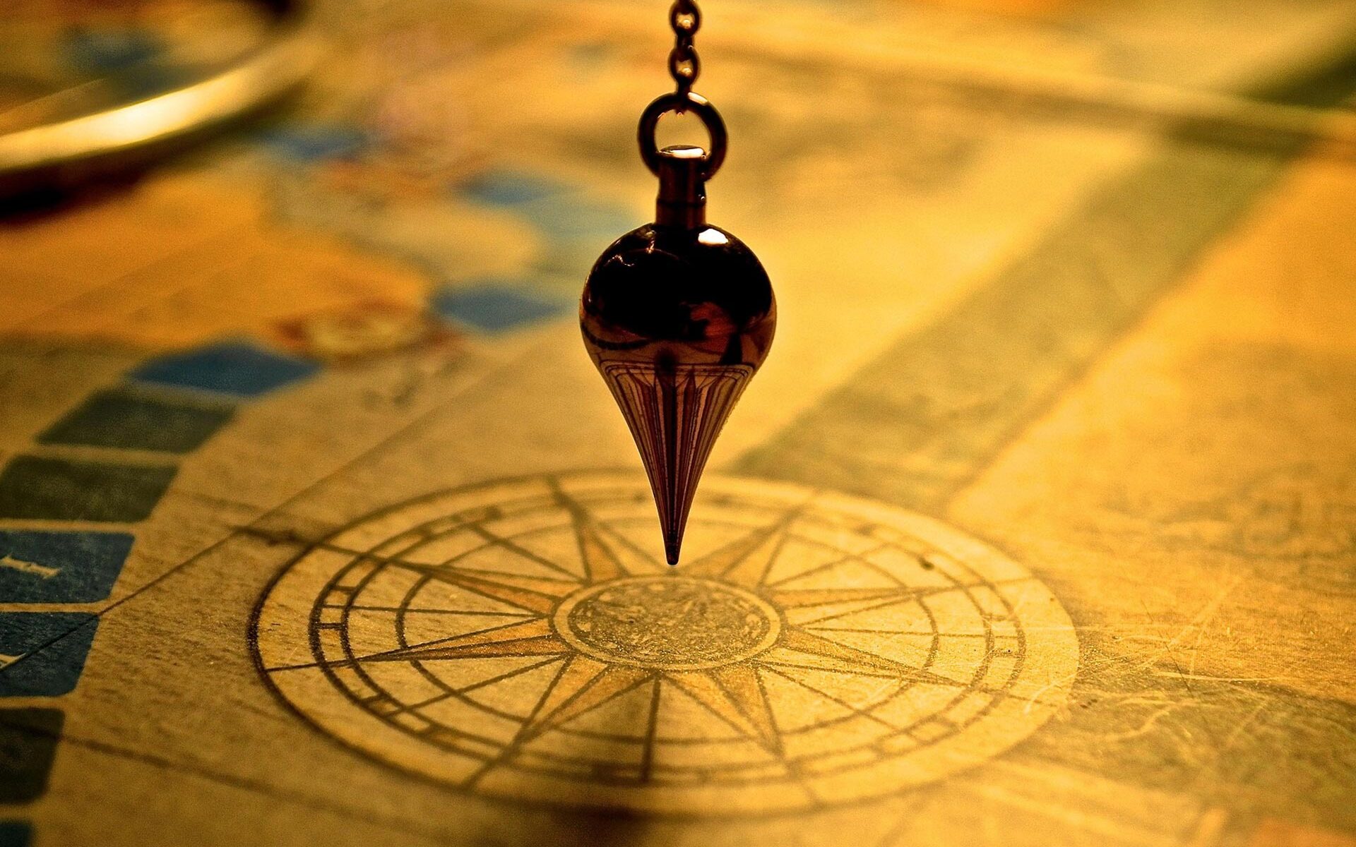 Ein goldenes Pendel über einer Kompassrose hängend.