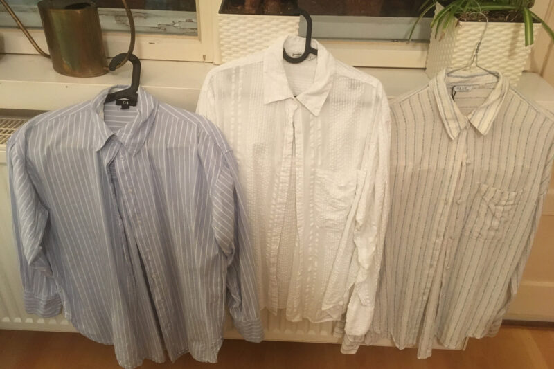 Drei Blusen auf Bügeln vor einer Heizung, zum Trocknen