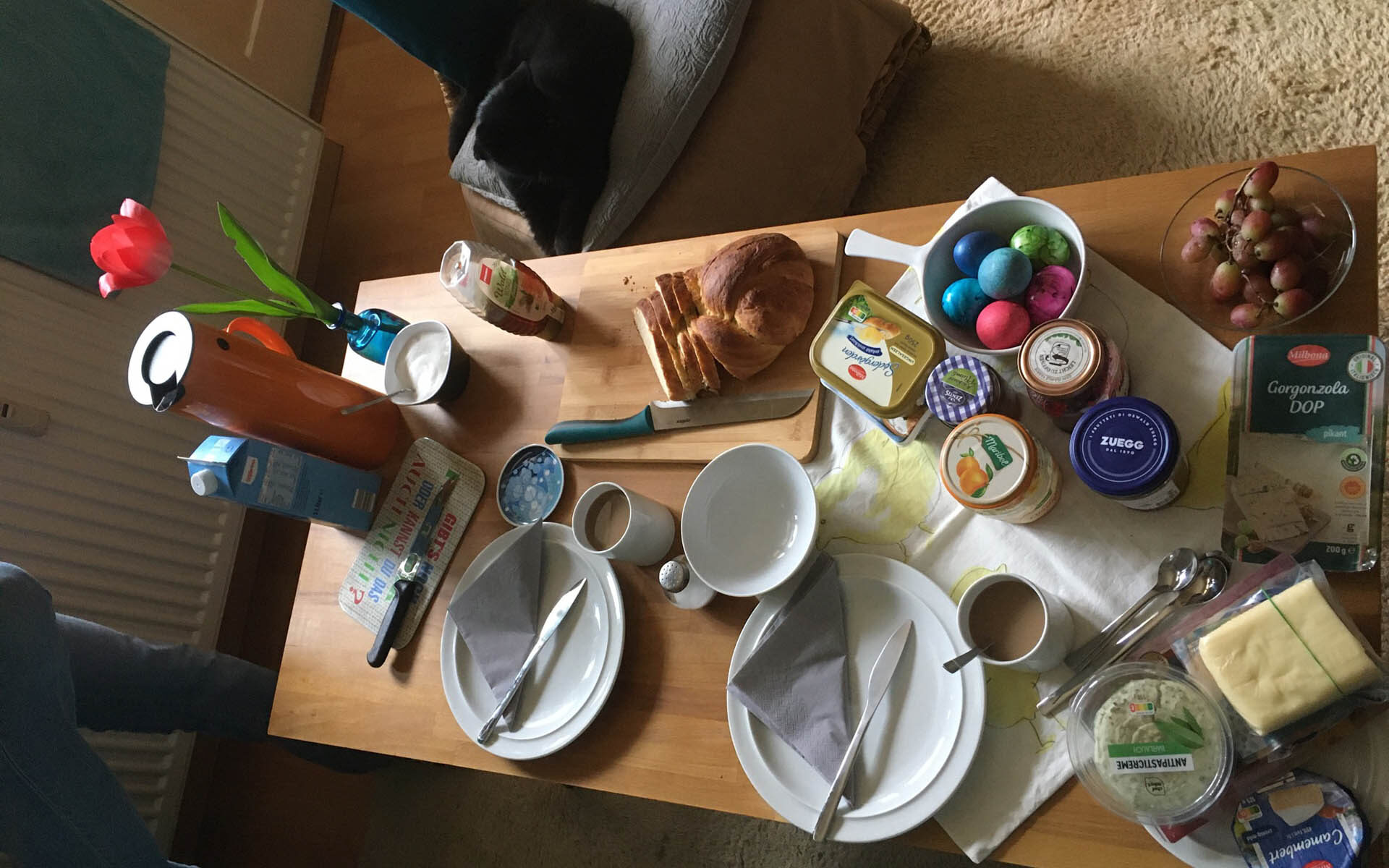 Ein Frühstückstisch an Ostern, mit bunten Eiern und Hefezopf.