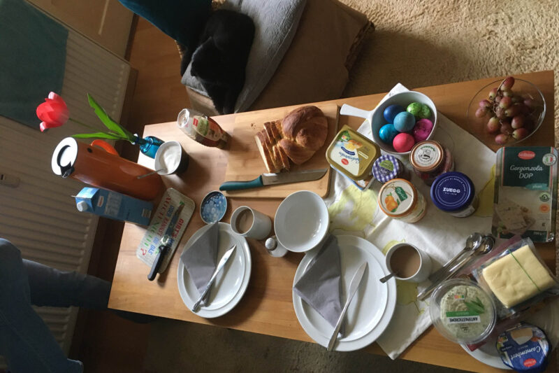 Ein Frühstückstisch an Ostern, mit bunten Eiern und Hefezopf.